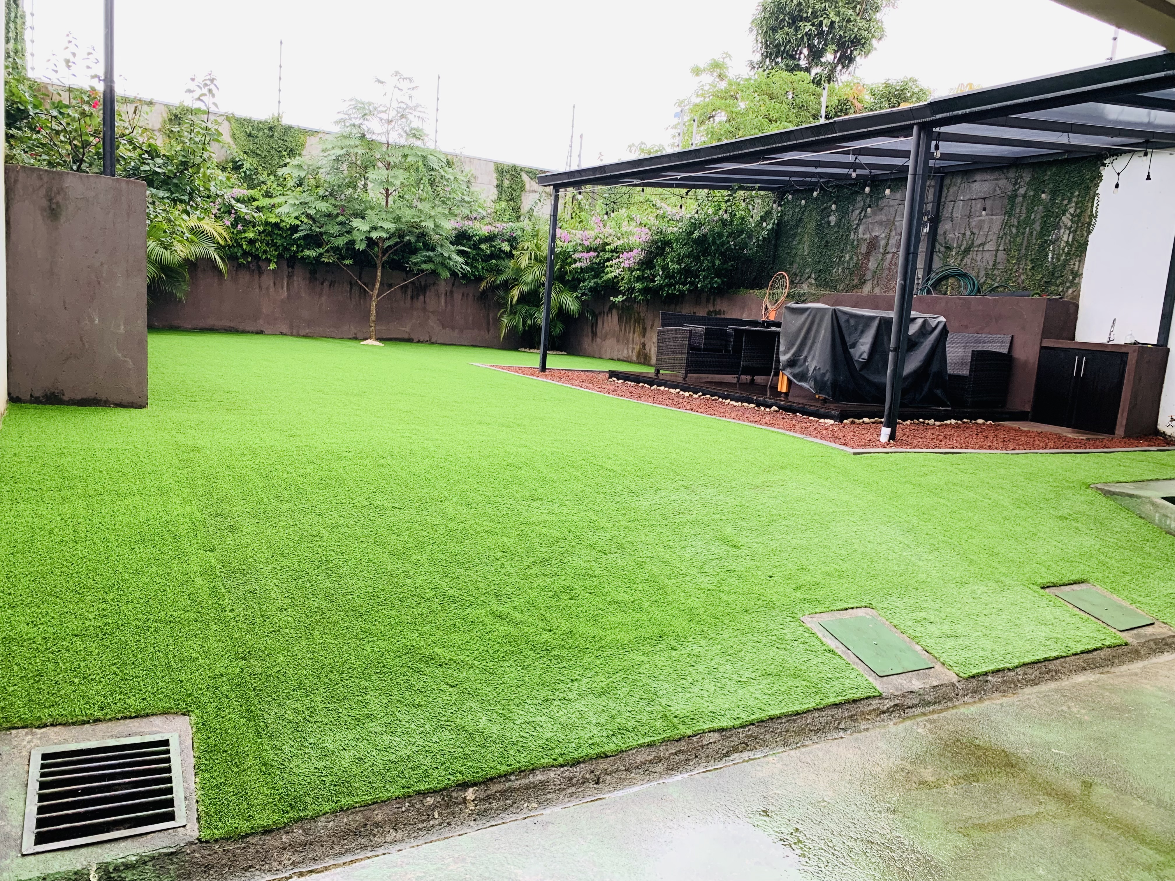 Patio con zacate sintético, pérgola y zona de BBQ